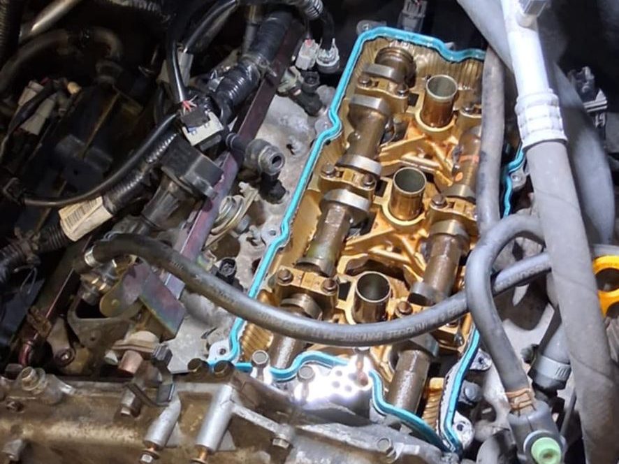 Cache-culbuteurs déposé sur un V6 Nissan : arbres à cames à nu et joint d'étanchéité neuf posé sur le plan de joint — Formula Pneus à Sens