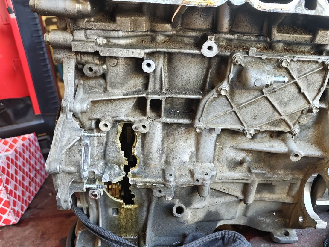 Vue d'ensemble du bloc moteur Toyota 2ZR détruit, carter-cylindres ouvert sur toute sa hauteur après une coulée de bielle