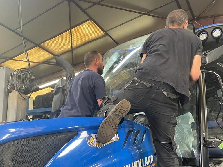 Vitrage neuf posé sur la cabine d'un tracteur New Holland, intérieur protégé pendant l'intervention
