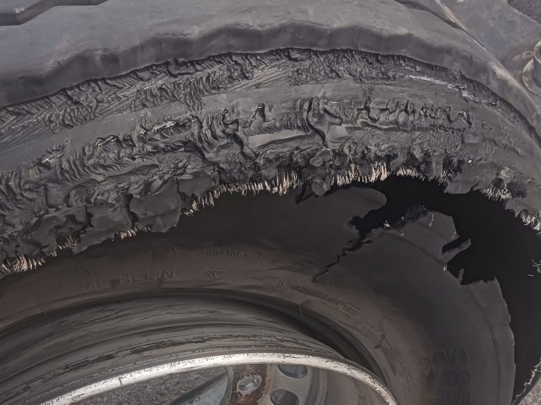 Pneu poids lourd éclaté : bande de roulement arrachée et carcasse métallique à nu après un roulage en sous-gonflage