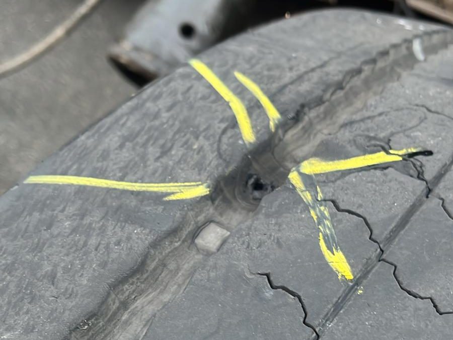Perforation repérée et marquée au marqueur jaune sur la bande de roulement d'un pneu poids lourd avant réparation