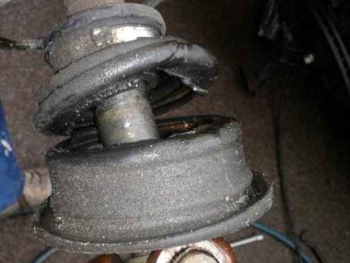 Jambe de suspension déposée à l'atelier : butée d'amortisseur, soufflet de protection et roulement de coupelle sortis, avant remplacement — Formula Pneus à Sens